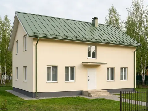 Дом с зелёной кровлей, кремовыми стенами и тёмно-серым цоколем