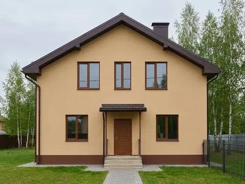 Дом с песочными стенами и коричневым цоколем